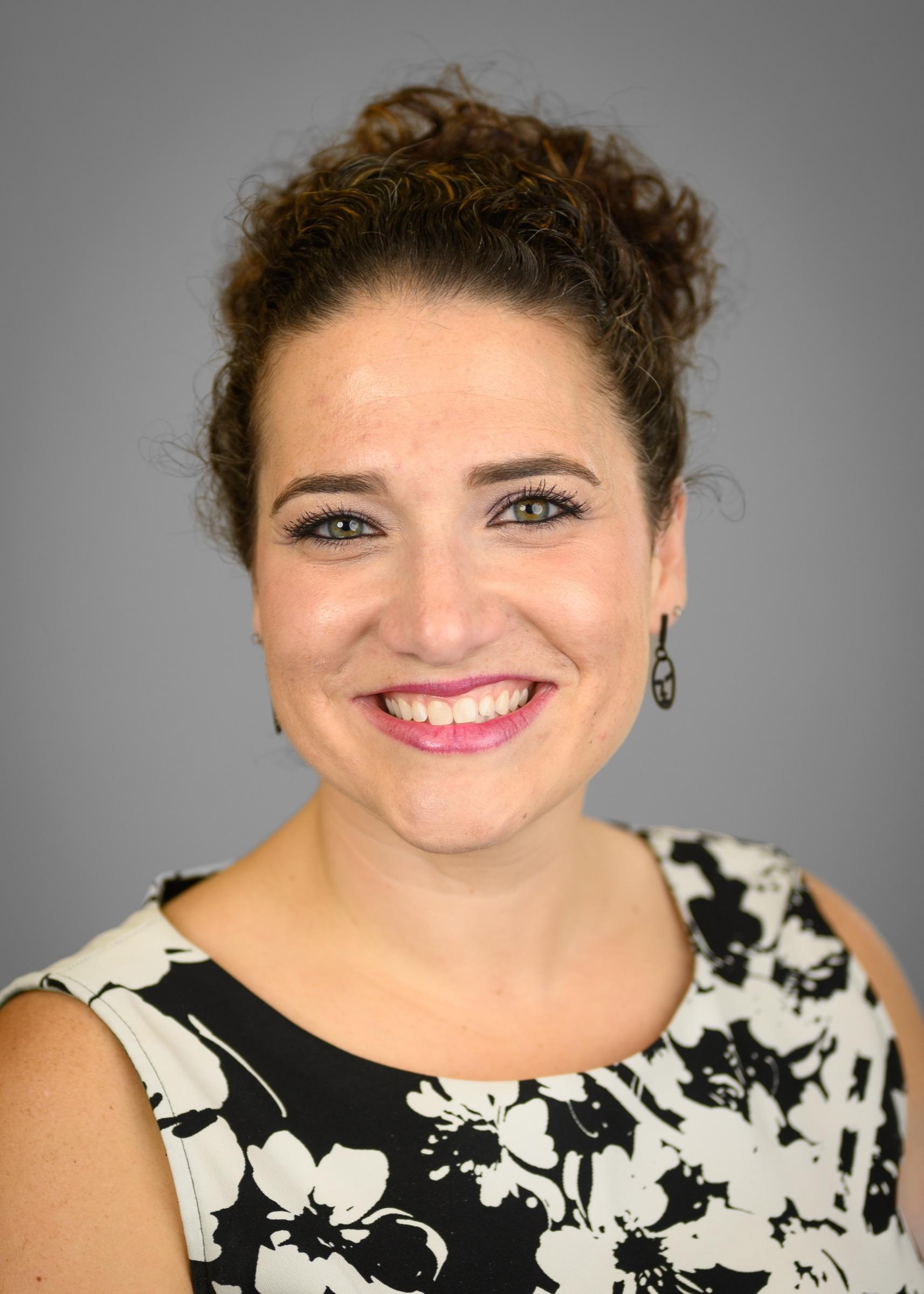 Nicole Stephenson studio headshot in a black-and-white floral top.