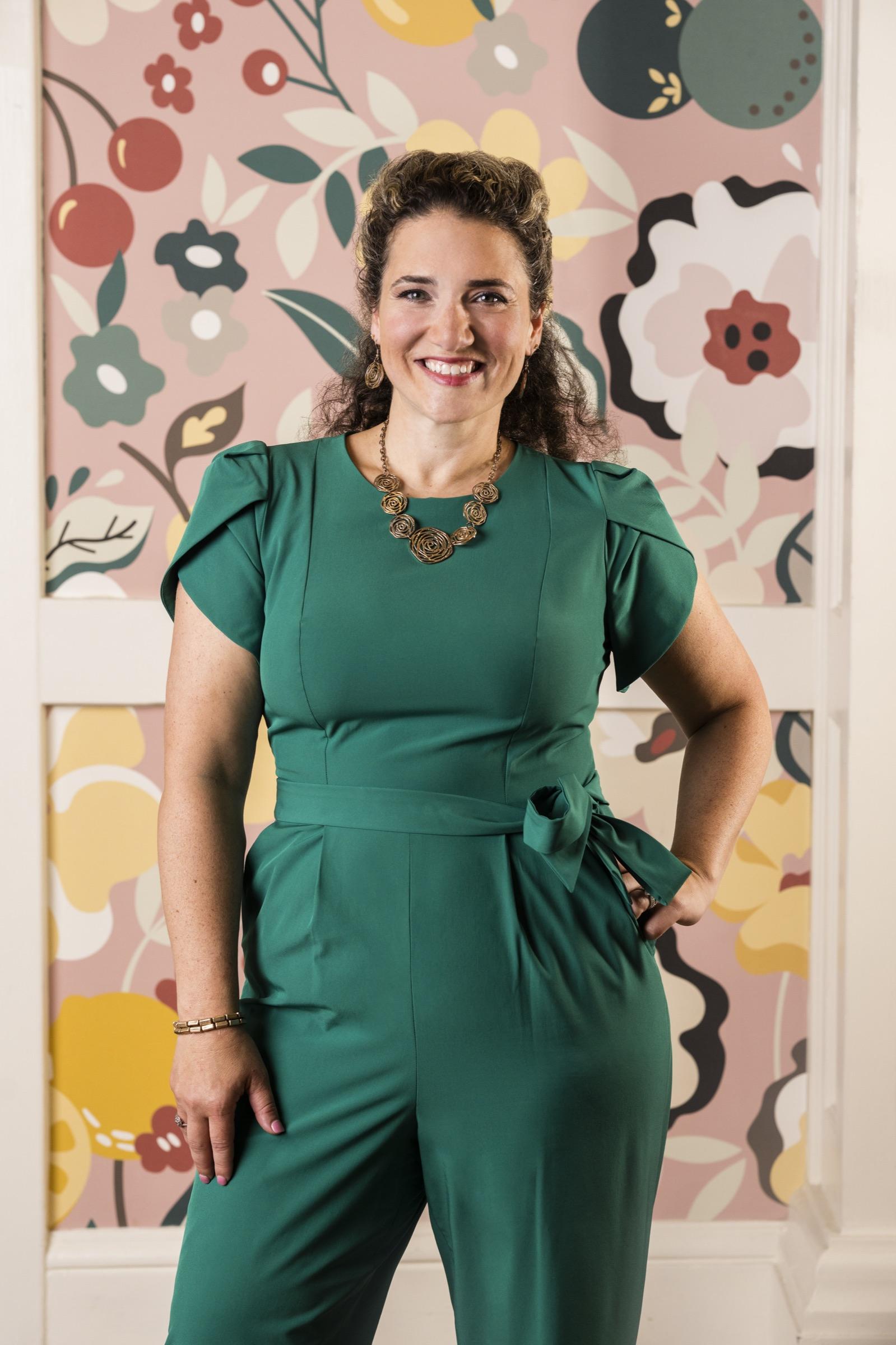 Nicole Stephenson — editorial portrait in an emerald green dress against a floral background, from Main Line Today's 2024 Power Women feature.